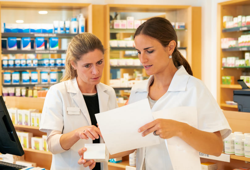Farmacéuticas colaborando en la oficina de farmacia en la revisión de recetas y medicamentos.
