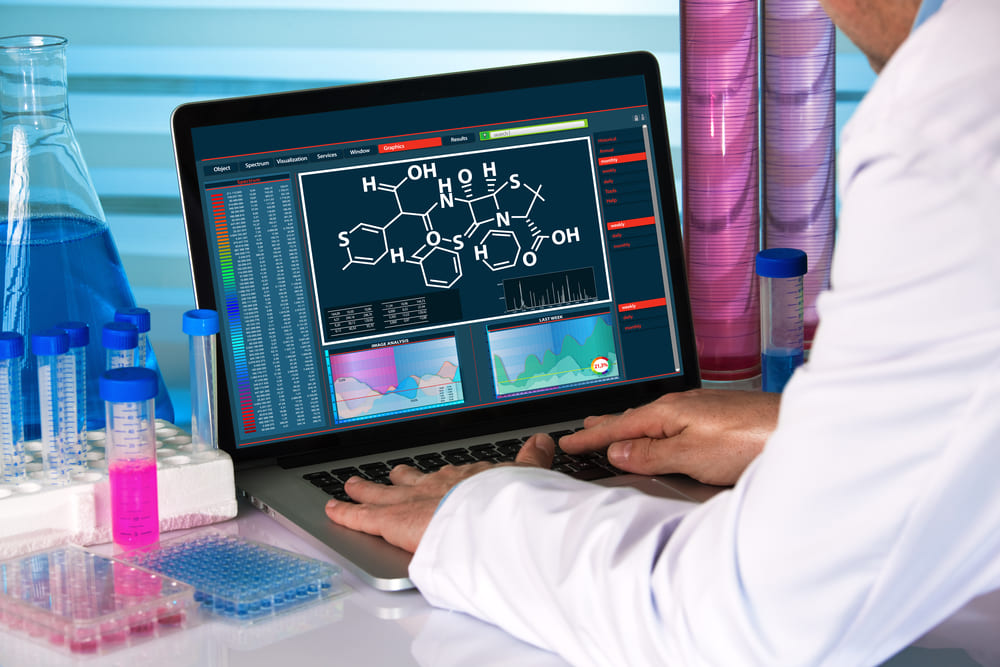 Profesional farmacéutico analizando fórmulas químicas y datos de laboratorio en ordenador con software BitFarma.